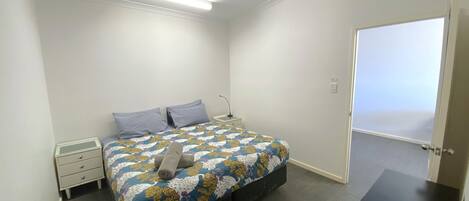 A bedroom with a bed, nightstand, and a door leading to a balcony.