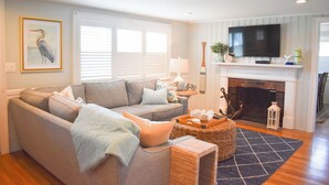 A living room with a sofa, a fireplace, a television, and a framed picture on the wall.