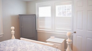 A bedroom with a bed, a dresser, a cabinet, and a window with blinds.
