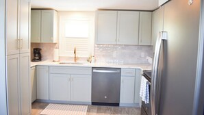 A modern kitchen with light blue cabinets, a stainless steel dishwasher, and a refrigerator.