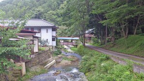 A rural setting with traditional houses, a stream, and a road. - Nakaya Ryokan (Ueda)