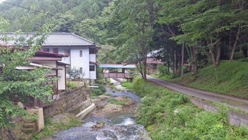 Entorno rural con casas tradicionales, un arroyo y una carretera.