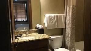 A bathroom with a granite countertop sink, a toilet, and a shower curtain. - Upscale slope side resort in Breckenridge, CO (Breckenridge)