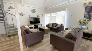 A modern living room with two sofas, a TV, and decorative fish wall art. - Osprey Holiday Village Unit 121 - Villa with a Pool in the Complex (EXMOUTH)