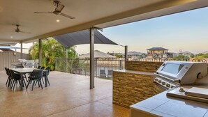 Une terrasse extérieure équipée d’un barbecue, d’une table à manger et de chaises.