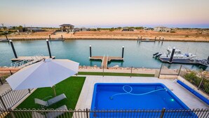 Une piscine avec vue sur un port de plaisance et des maisons en arrière-plan.