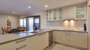 Kitchen features a central island with sink and dishwasher, adjacent dining area with table and chairs.