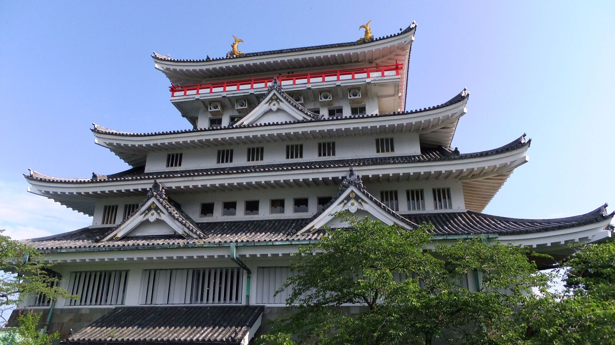 Un edificio japonés tradicional de varios niveles con barandilla roja en el nivel superior.
