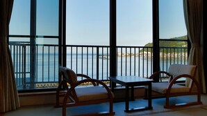 A balcony with a view of the sea, two wooden chairs, and a small table. - Atami Onsen Hiratsuru (Atami)