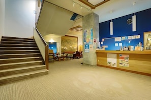 A hotel lobby with a staircase, a reception desk, and a seating area. - Atami Onsen Hiratsuru (Atami)
