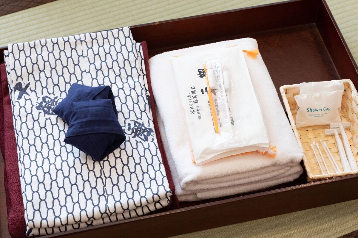 A wooden tray with towels, a folded towel, and a shower cap.