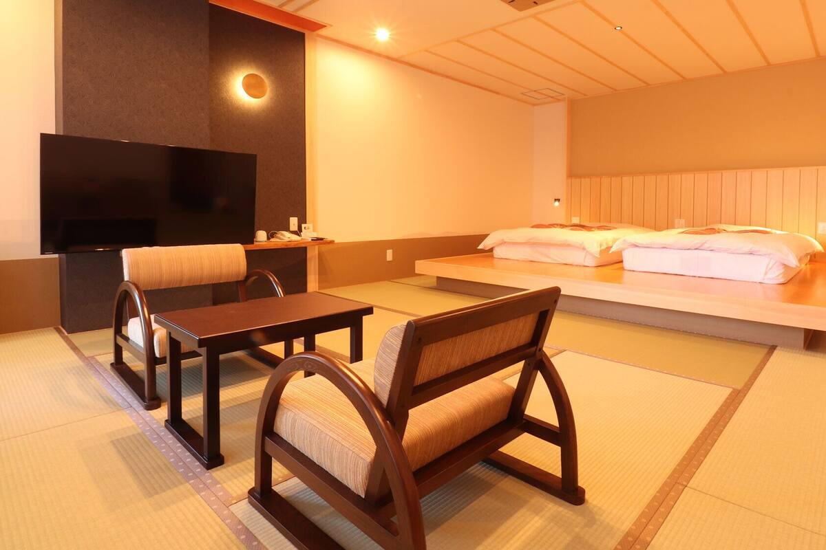 A hotel room with a bed, a TV, a desk, and a chair.