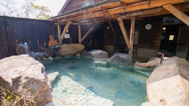 A clear outdoor hot spring area with wooden structures and large rocks. - Shibi Yu-no-yado Kusunoki (Satsuma)