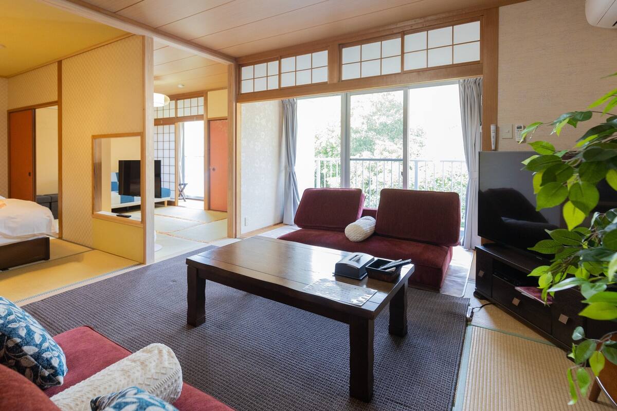 Camera d'albergo con un letto, un divano, un tavolino da caffè, una TV e un'ampia finestra.