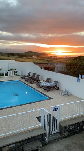 A pool area with lounge chairs and a view of the sunset over the landscape. - Pôr do Sol is an accommodation located in R.Grande,close to Santa Barbara beach  (Ribeira Grande)