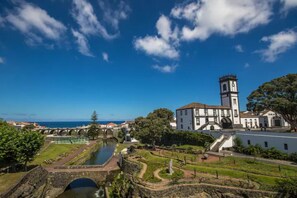 A historic building with a clock tower, a bridge, and a river. - Pôr do Sol is an accommodation located in R.Grande,close to Santa Barbara beach  (Ribeira Grande)