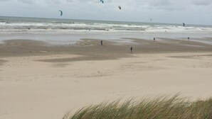 Een strand met een zandstrand en grasduinen op de voorgrond.