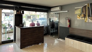 A reception area with a wooden desk, a bench, and a fire extinguisher on the wall. - Hotel Xenios (Macapa)