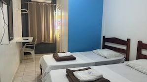 A hotel room with two beds, a desk, and an air conditioning unit. - Hotel Xenios (Macapa)