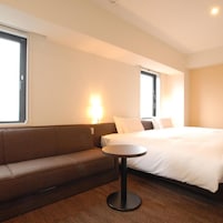 Una habitación de hotel con una cama, un sofá, una mesita redonda y una ventana.