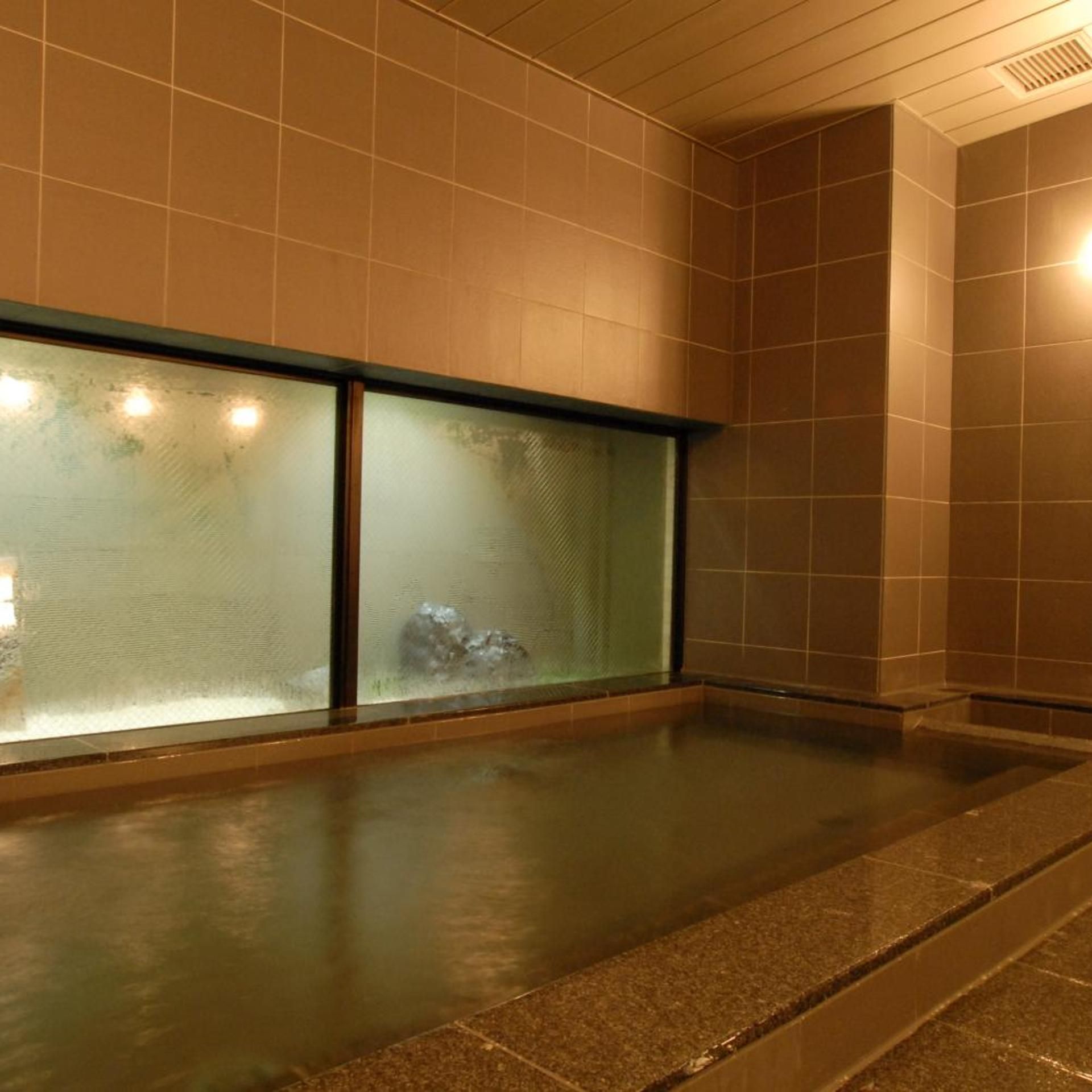A spa area with a large glass wall, a tiled floor, and a ceiling vent.