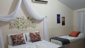 A bedroom with a bed, two pillows, a blanket, a wall decoration, and a small bedside table.