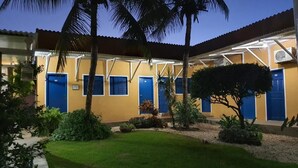 A building with multiple blue doors, a well-maintained lawn, and palm trees.