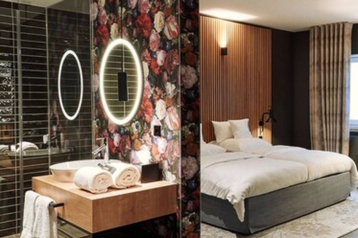 A modern bedroom with a large bed, a wooden vanity with a mirror, and a floral wallpaper design.