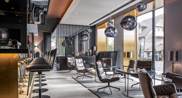 Un interior moderno con sillones de cuero, una zona de bar y grandes ventanales que dan a la calle.