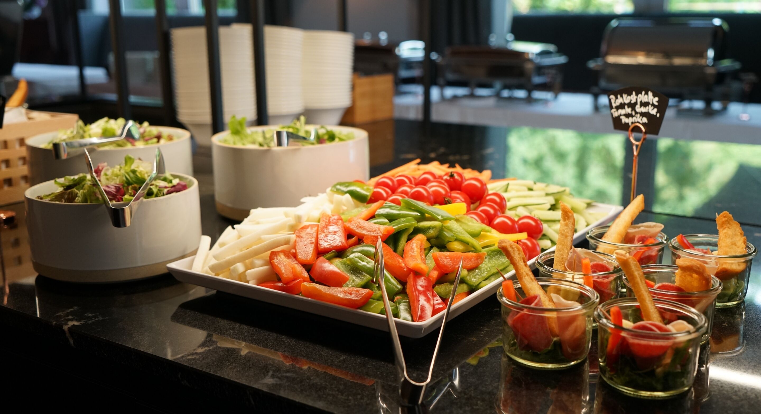 Ein Buffet mit verschiedenen Speisen, darunter Salate, Gemüse und Vorspeisen.