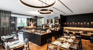 A modern restaurant with a central bar, dining tables, and a seating area with a sofa. - Hotel WunnersWat (Verl)