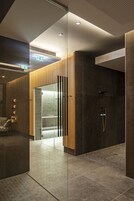 Un baño moderno con mampara de vidrio, zona de ducha y un mostrador de recepción.
