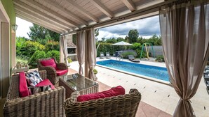 A covered outdoor area with wicker furniture, a pool, and a view of the garden. - Spacious holiday house / pool / jacuzzi / playground / 6+2 (Rakalj)