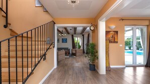 A spacious living area with a staircase, wooden flooring, and a view of an outdoor pool. - Spacious holiday house / pool / jacuzzi / playground / 6+2 (Rakalj)