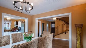 A spacious living room with wicker furniture, a chandelier, and a view of the kitchen and staircase. - Spacious holiday house / pool / jacuzzi / playground / 6+2 (Rakalj)