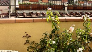 A balcony with terracotta roof tiles, a wrought iron fence, and a rose bush. - Santa Croce Terrace - Luxury nest (Firenze)