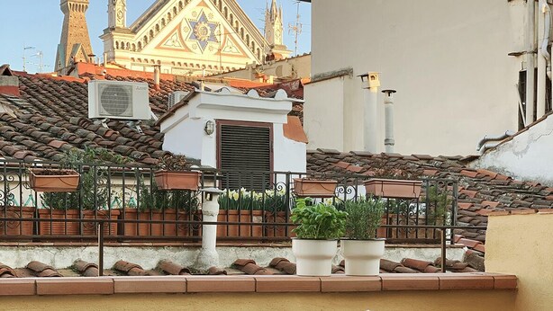 A balcony with a wicker sofa, a glass table, and potted plants. - Santa Croce Terrace - Luxury nest (Firenze)