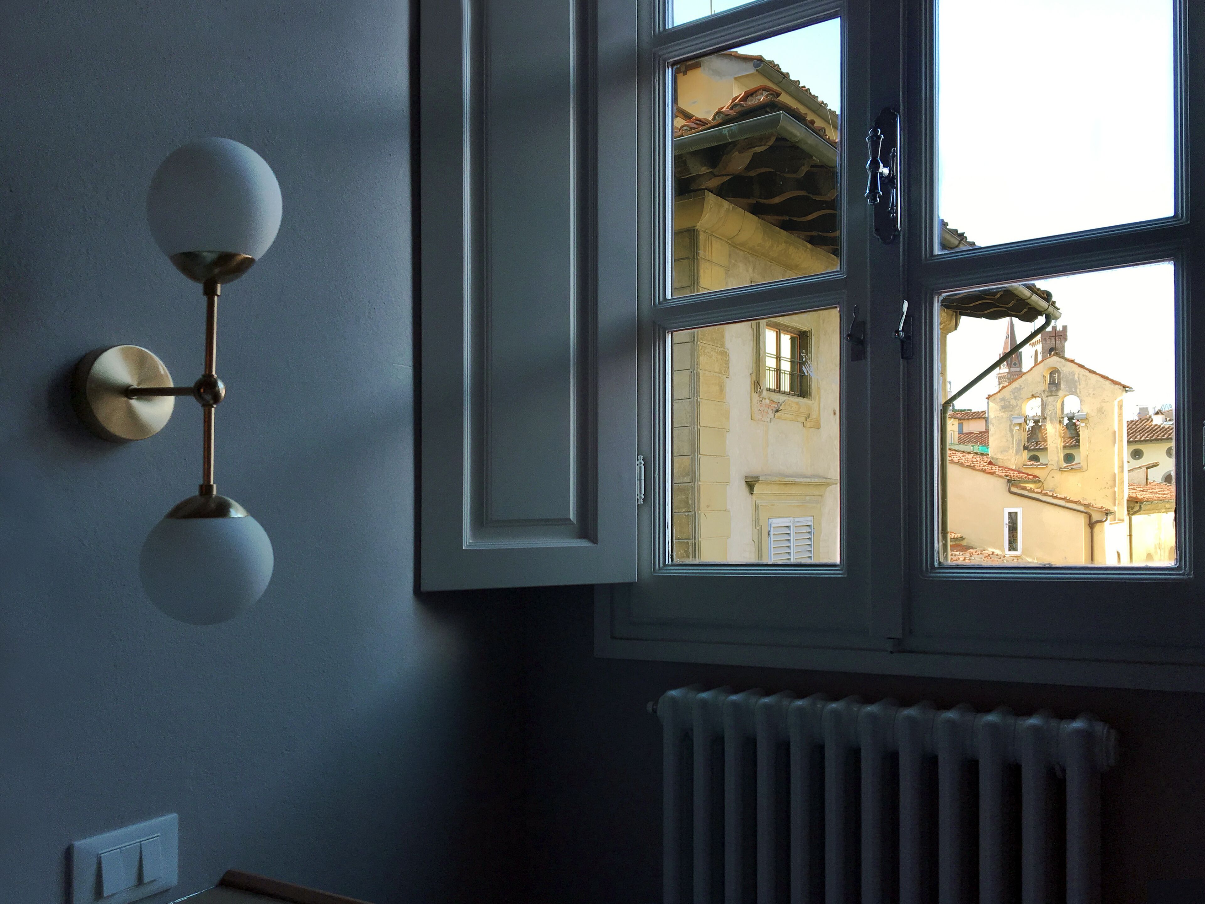 A room with a large window, a radiator, and a wall-mounted light fixture.