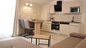 A modern kitchen with a stone wall backsplash, a microwave, and a dishwasher. There is a dining area with a table and chairs.