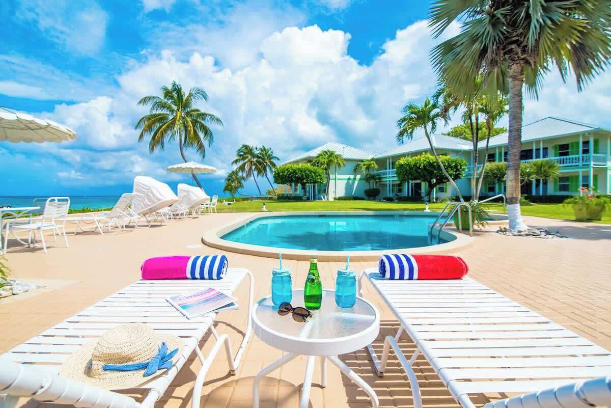 Ein Poolbereich mit Liegestühlen, einem kleinen Tisch mit Getränken und einem Pool.