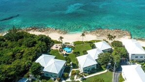 An aerial view of a coastal property with a swimming pool, multiple buildings, and a beach. - Oceanfront 2 BR & Pool - Cocoplum #5 on 7 Mile (7 Mile Beach)