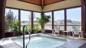 A hot tub with a wooden ceiling and large windows overlooking a residential area.