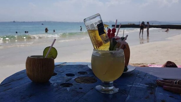 A beachside table with a drink and a coconut shell. - Palmetto Sunset (Cartagena)