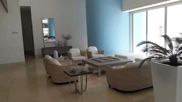 A modern living room with a sofa set, a coffee table, and a large potted plant.