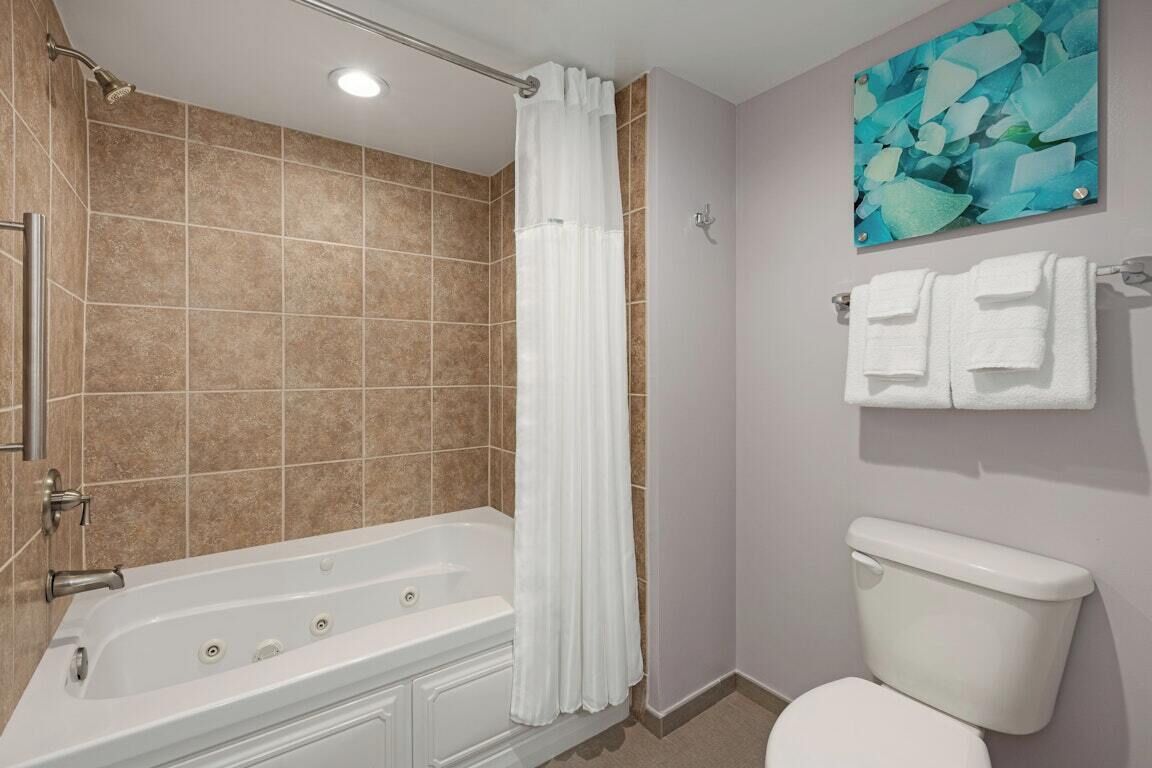 A bathroom with a bathtub, toilet, and a shower curtain.