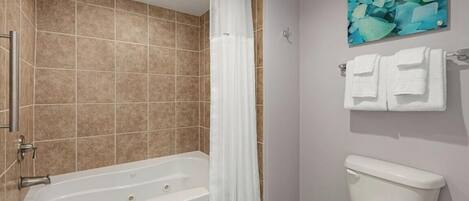 A bathroom with a bathtub, toilet, and a shower curtain.