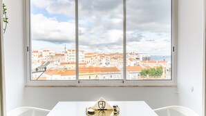 Ein Zimmer mit großem Fenster und Blick auf eine Stadtlandschaft.