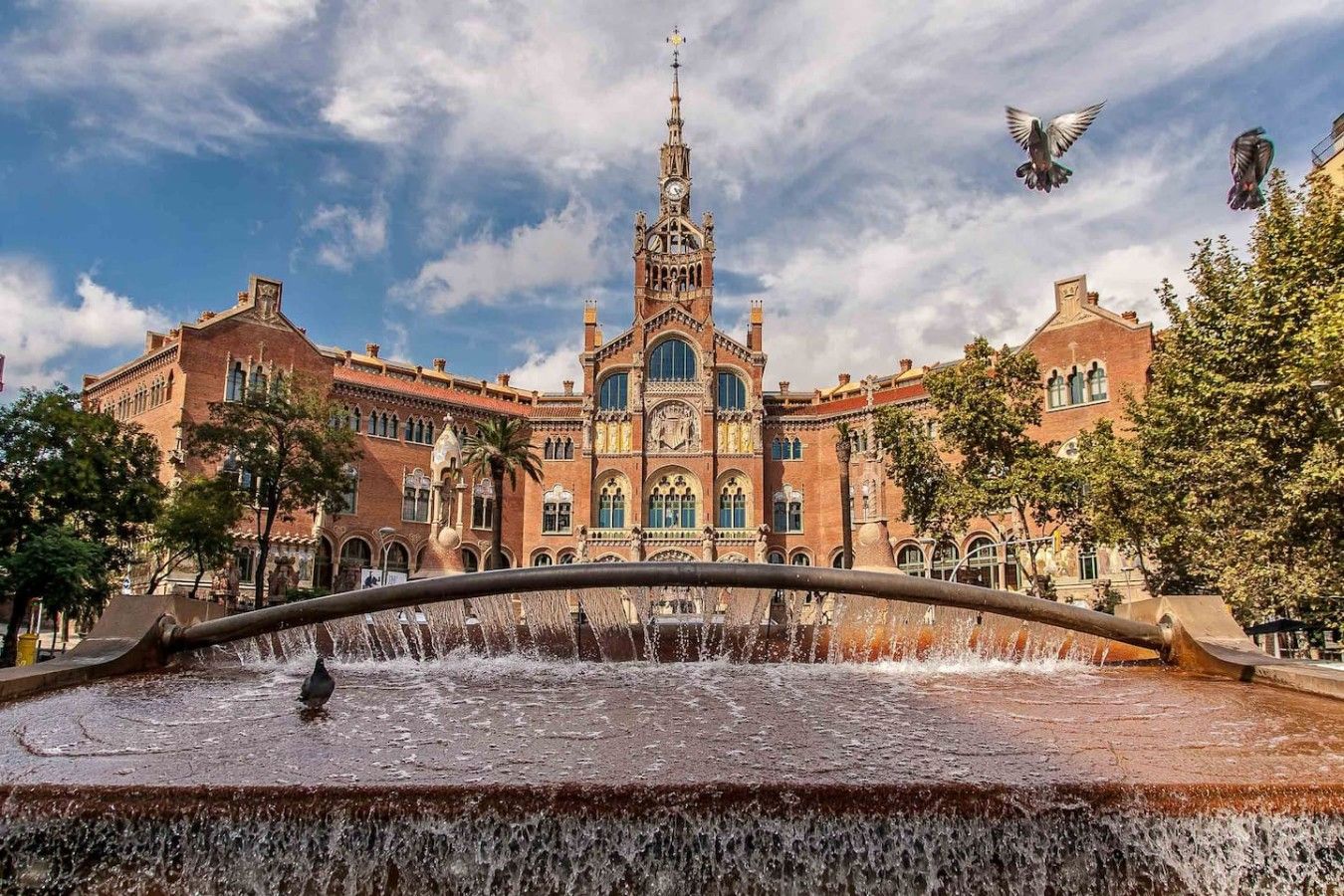 Un edificio histórico con una torre central y una fuente en primer plano.