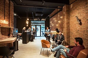 Interior d'una cafeteria amb parets de maó, llums penjants i persones assegudes a taules.