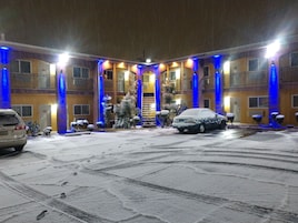 Un hotel con un espacio exterior cubierto, varios balcones y una escalera central.